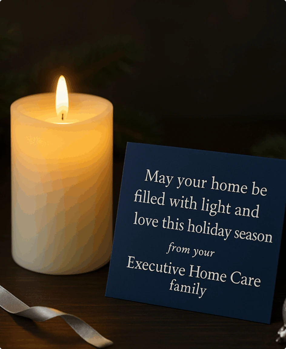 A lit candle sits beside a card reading “May your home be filled with light and love this holiday season from your Executive Home Care family.”